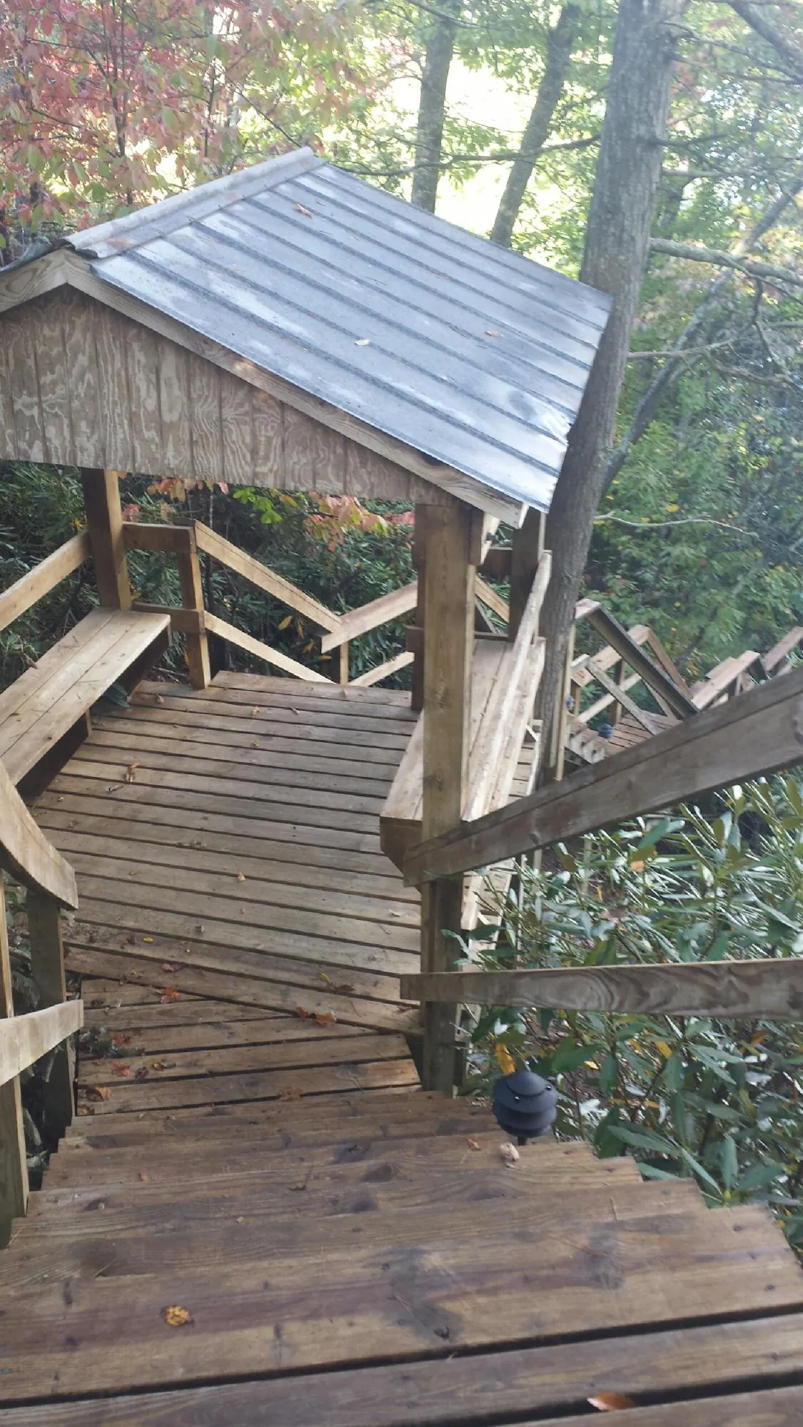 Metal roofed shelter over wooden steps on a wooded walkway — Skylight Repair & Installation work by our crew in Kinsman